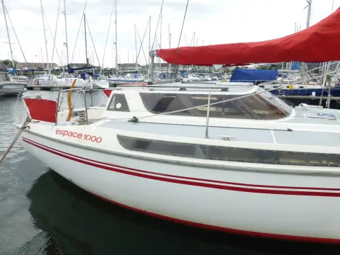 Jeanneau Espace 1000: bow quarter showing Espace 1000 decal, wrap-round wheelhouse windows and red sprayhood