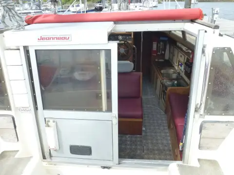 Jeanneau Espace 1000: open sliding door from cockpit looking into wheelhouse with burgundy seating
