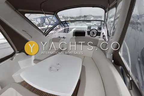 Jeanneau Leader 8: cockpit under canopy with white table, seating and helm position ahead