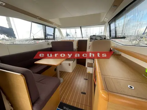 Jeanneau Merry Fisher 10: saloon with grey upholstered dining seating, wooden table and wood-effect floor