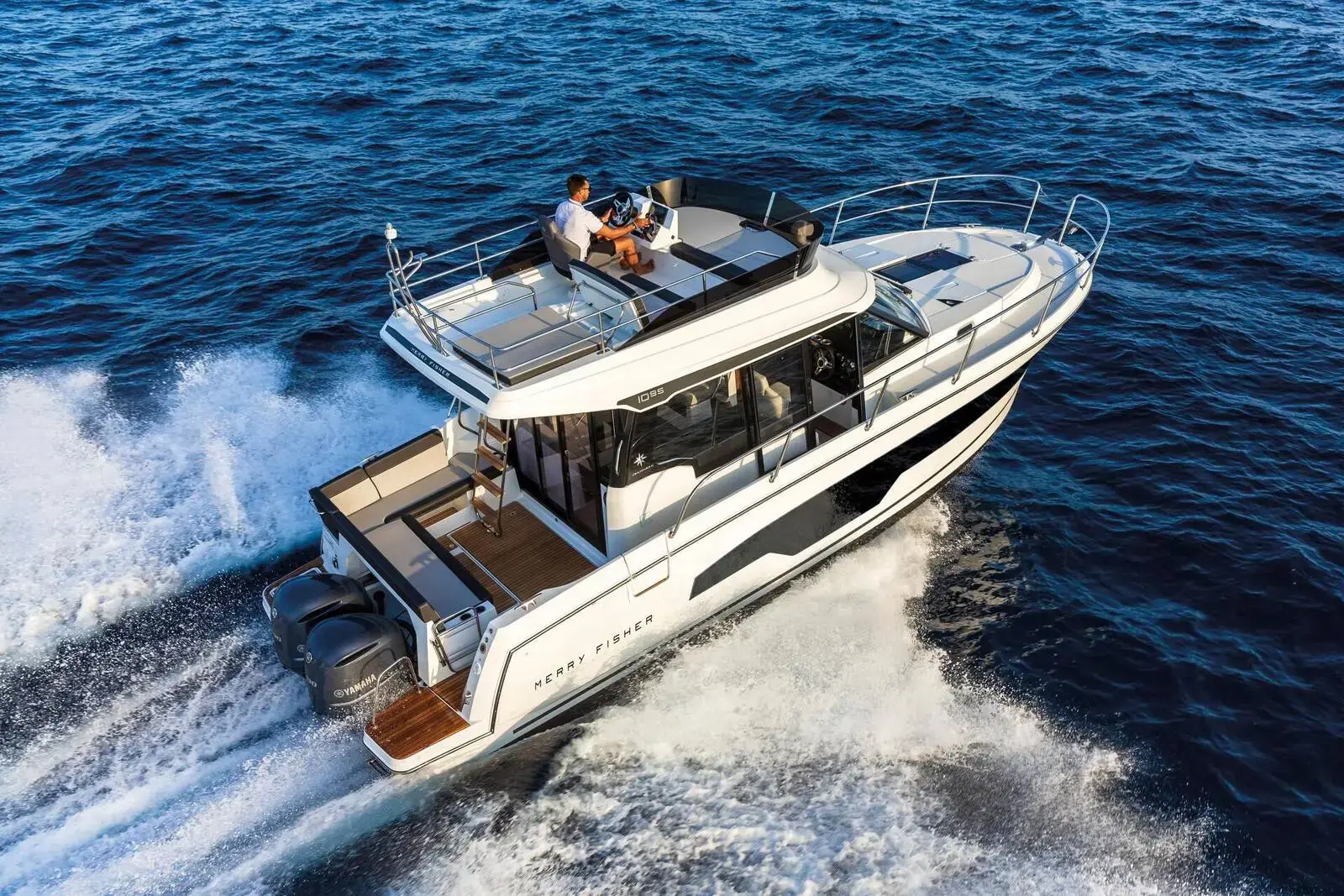 Jeanneau Merry Fisher 1095 Fly: aerial view of the white hull under way at speed, people relaxing on the flybridge
