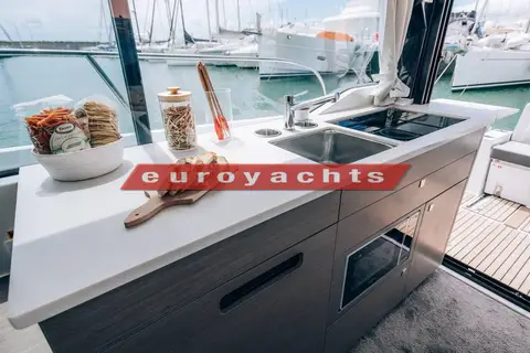 Jeanneau Merry Fisher 1095 Fly Serie 2: galley worktop with sink and hob beside the cockpit, marina visible outside