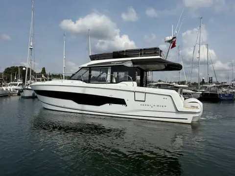 Jeanneau Merry Fisher 1295 Fly: starboard side profile showing flybridge hardtop and red ensign at the stern