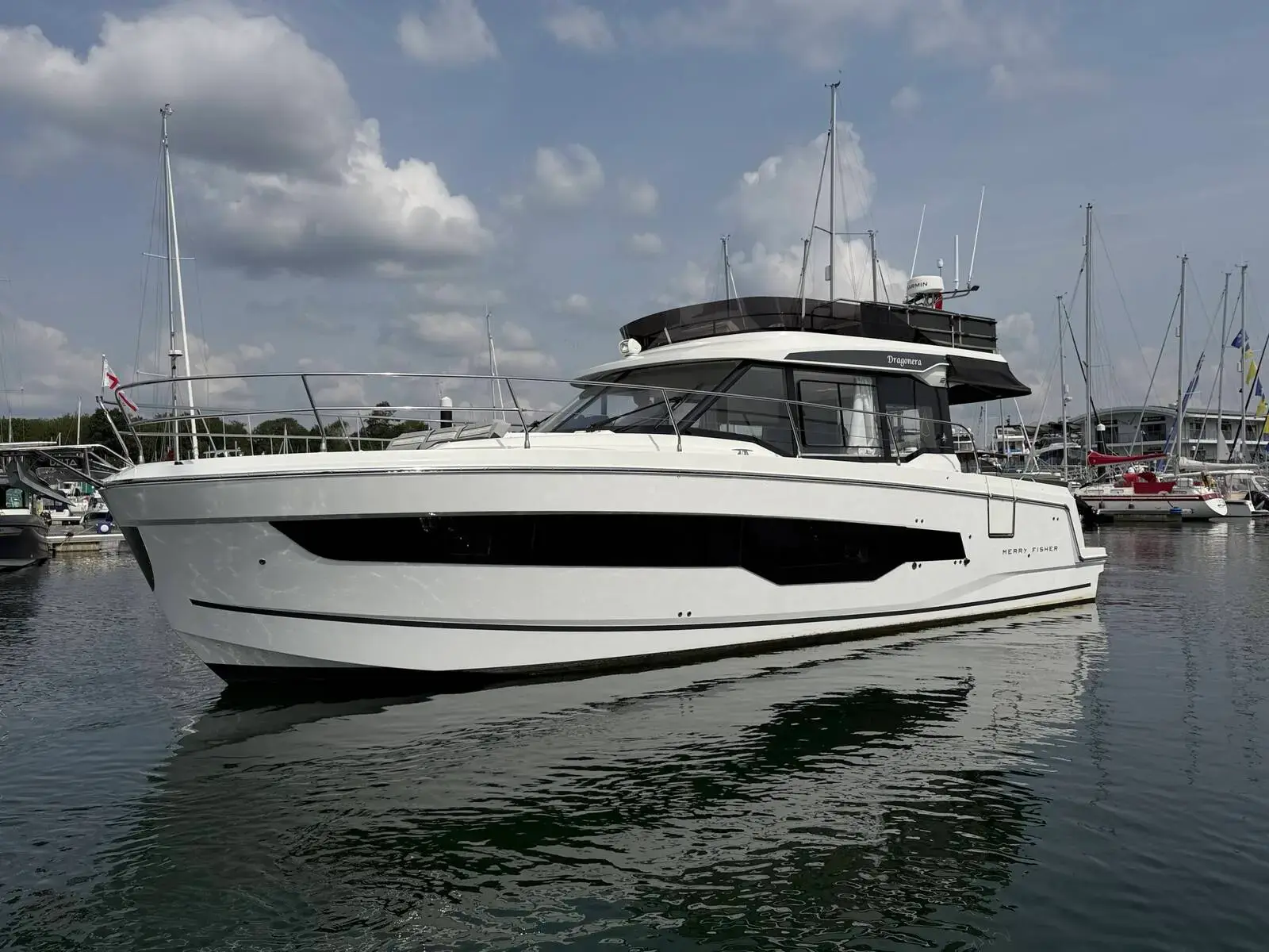 Jeanneau Merry Fisher 1295 Fly: white flybridge hull with dark hull window band, moored in a calm marina