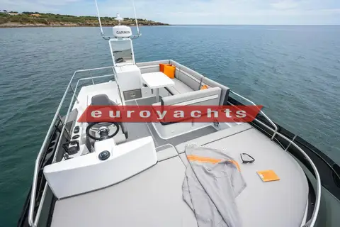 Jeanneau Merry Fisher 1295 Fly S2: flybridge helm seat and wheel with L-shaped seating and table, coastline behind