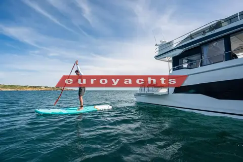 Jeanneau Merry Fisher 1295 Fly S2: paddleboarder alongside the stern and starboard side at anchor near a headland