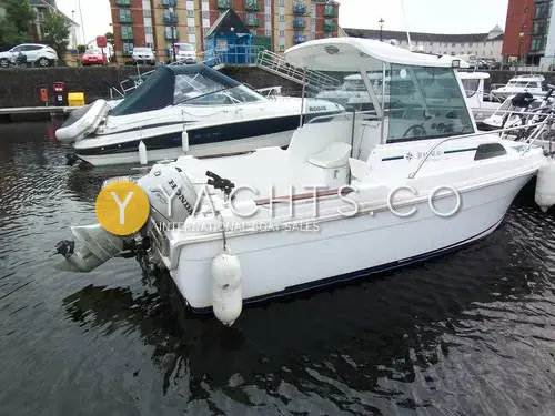 Jeanneau Merry Fisher 530: stern quarter view in a marina showing the Honda outboard, aft cockpit and wheelhouse