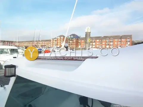 Jeanneau Merry Fisher 530: wheelhouse roof with wooden grab rail, marina and apartment buildings behind