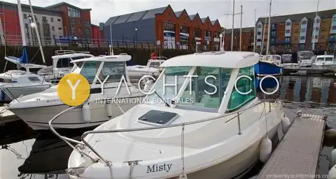 Jeanneau Merry Fisher 585: wider view of the boat on her pontoon berth with fenders out and marina buildings behind