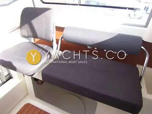 Jeanneau Merry Fisher 6 Marlin: wheelhouse seating with grey folding seat and dark upholstered bench with rod holders behind