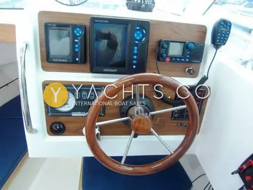 Jeanneau Merry Fisher 605: helm with wooden wheel, Navman plotter, fishfinder and VHF radio set in wood-effect panel