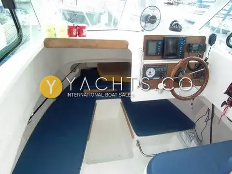 Jeanneau Merry Fisher 605: wheelhouse interior with blue cushioned berths in the cabin forward of the helm station