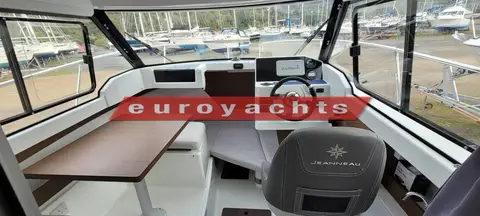 Jeanneau Merry Fisher 605: wheelhouse with wood-effect dinette table, grey upholstered seating and helm chair