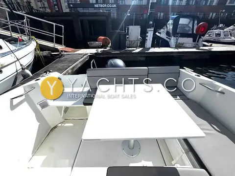 Jeanneau Merry Fisher 605 S2: cockpit table set up between bench seats, looking aft over the transom to the marina