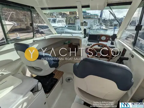 Jeanneau Merry Fisher 625: wheelhouse interior with navy and cream helm and co-pilot seats and wooden wheel