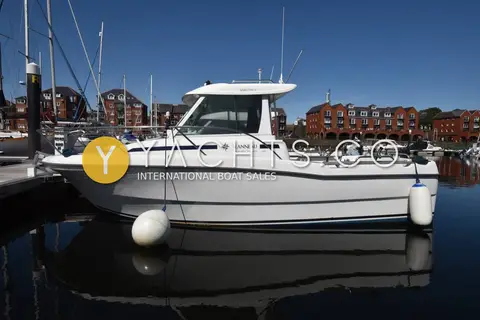 Jeanneau Merry Fisher 635: starboard profile alongside a pontoon, red brick waterfront buildings behind