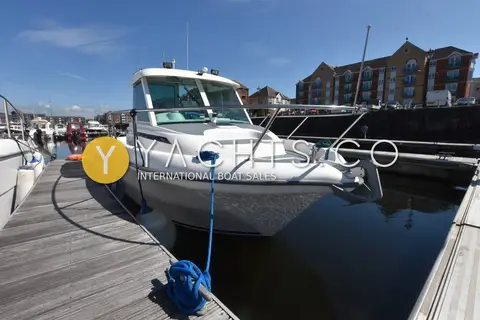 Jeanneau Merry Fisher 635: starboard bow on the pontoon with blue mooring line and apartment buildings behind