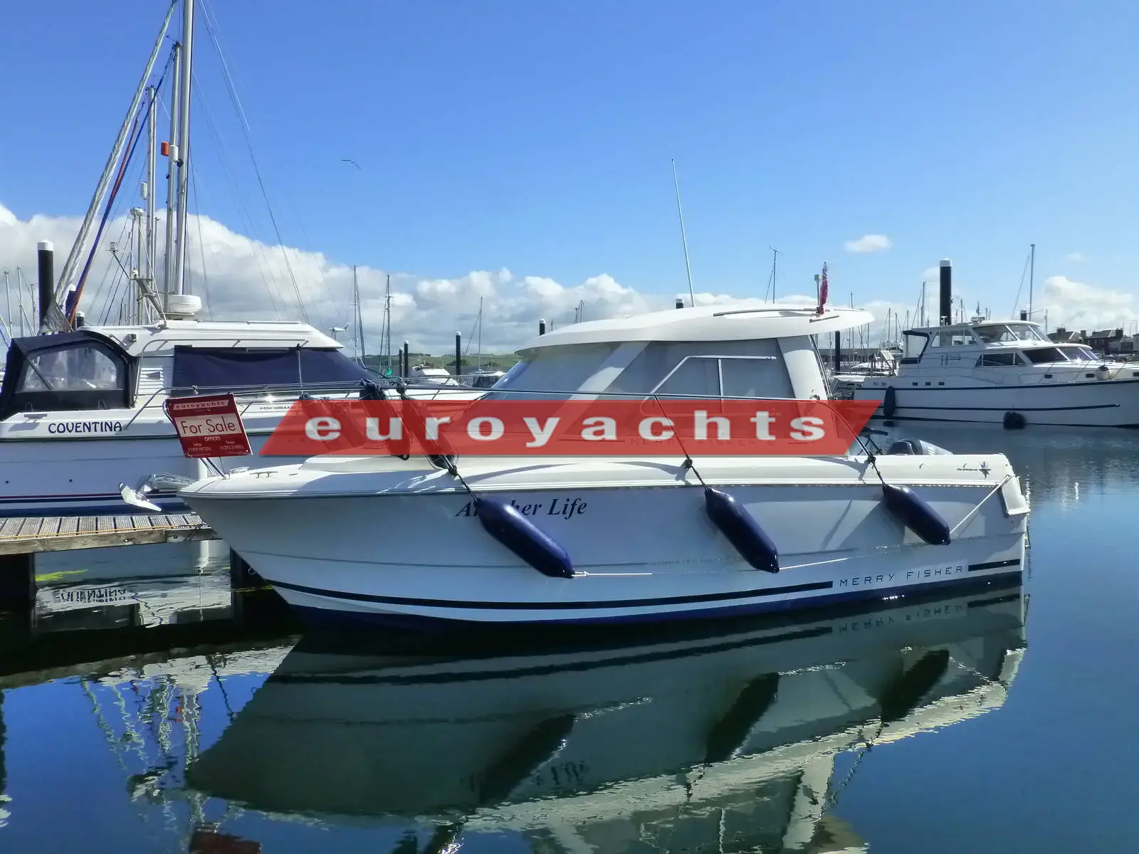 Jeanneau Merry Fisher 645: white wheelhouse motor boat moored alongside a pontoon in a marina on a sunny day