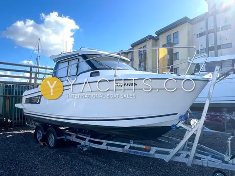 Jeanneau Merry Fisher 695: starboard side of the hull and wheelhouse on a trailer under blue sky