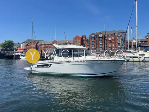 Jeanneau Merry Fisher 695: starboard side profile of the white hull and wheelhouse afloat in Swansea marina