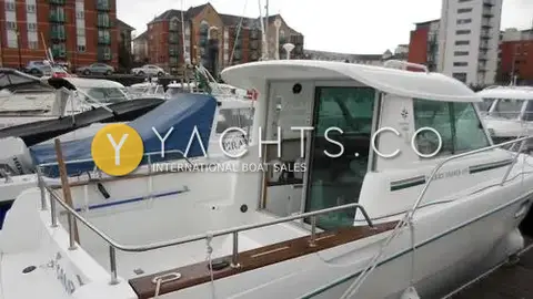 Jeanneau Merry Fisher 695: port side view of the pilothouse and cockpit with teak gunwale capping, moored in marina