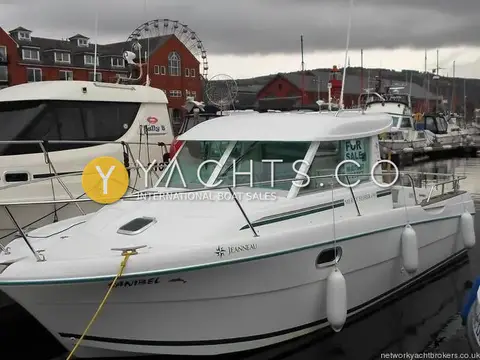Jeanneau Merry Fisher 695: starboard bow view of white hull at a pontoon with apartments and a big wheel behind