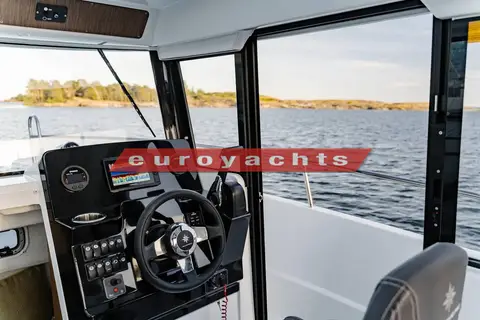 Jeanneau Merry Fisher 695 Sport: helm station with touchscreen chartplotter, wheel and open starboard door looking out to sea
