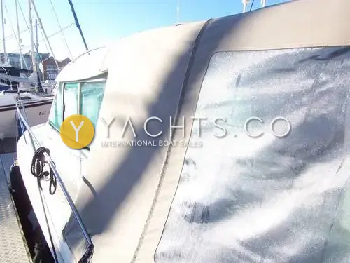 Jeanneau Merry Fisher 725: side deck and wheelhouse windows beside the grey camper canopy enclosing the cockpit