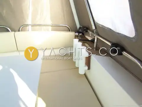 Jeanneau Merry Fisher 725: cockpit under the canopy with cream cushioned seating and three white rod holders