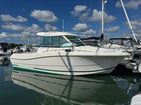 Jeanneau Merry Fisher 725: starboard bow view of the hull and wheelhouse alongside a pontoon under blue sky