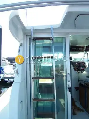 Jeanneau Merry Fisher 750 Reduced: stainless steel ladder with wooden treads beside the sliding wheelhouse door