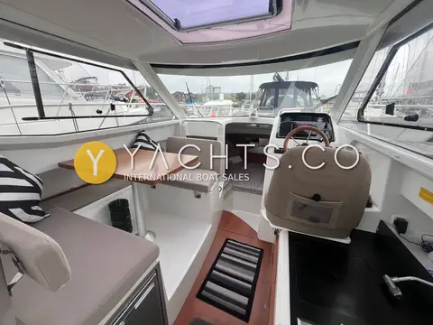 Jeanneau Merry Fisher 755: wheelhouse interior with dinette table to port, helm seat to starboard and roof hatch above