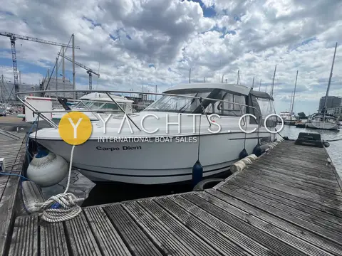 Jeanneau Merry Fisher 755: port bow view alongside a wooden pontoon, with fenders and mooring lines rigged