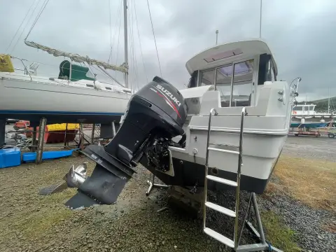 Jeanneau Merry Fisher 755: stern ashore showing the outboard tilted up and a boarding ladder