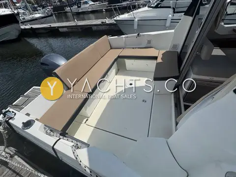 Jeanneau Merry Fisher 795: cockpit with L-shaped beige cushioned bench, outboard visible beyond the transom