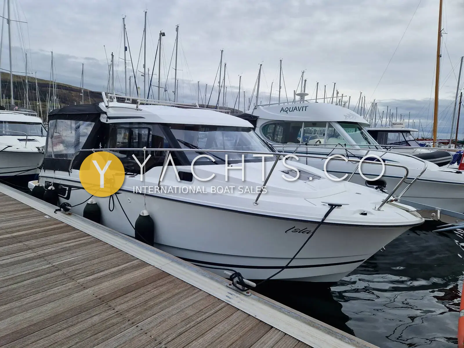 Jeanneau Merry Fisher 795: port bow view of the white hull moored alongside a pontoon in a busy marina