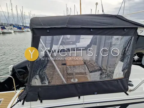 Jeanneau Merry Fisher 795: full black cockpit enclosure closed, with clear panel showing seating and table inside
