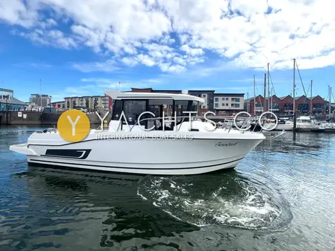 Jeanneau Merry Fisher 795 Marlin: starboard bow view of hull and black-windowed wheelhouse moving through marina water