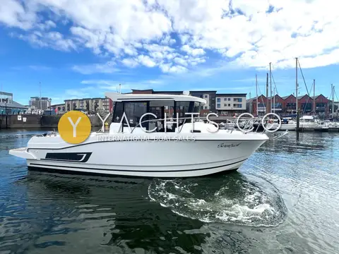 Jeanneau Merry Fisher 795 Marlin: starboard profile under way in marina with apartment blocks and moored yachts behind
