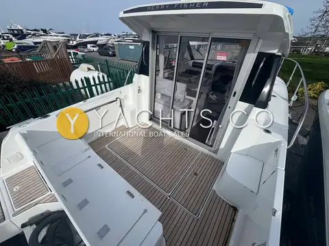 Jeanneau Merry Fisher 795 S2: cockpit with teak-effect floor looking forward to the wheelhouse sliding glass doors