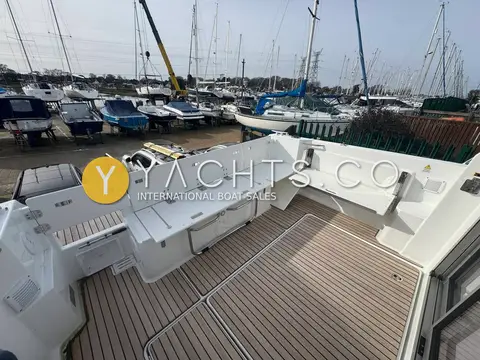Jeanneau Merry Fisher 795 S2: wider view of aft cockpit bench and teak deck with boats ashore behind
