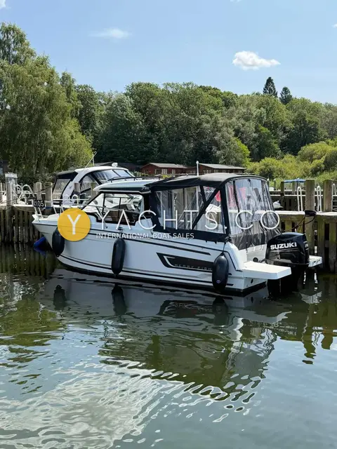 Jeanneau Merry Fisher 795 S2: starboard side view alongside a pontoon showing fenders, cockpit enclosure and outboard
