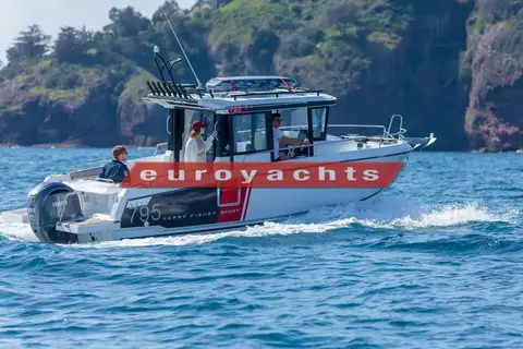 Jeanneau Merry Fisher 795 Sport: starboard side under way along a green rocky coastline, open aft cockpit and outboard visible