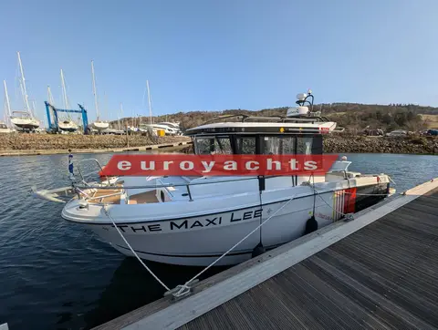 Jeanneau Merry Fisher 795 Sport S2: port bow quarter at the pontoon with hills and boatyard behind