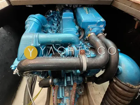 Jeanneau Merry Fisher 805: engine bay showing the blue diesel engine with black exhaust and hoses