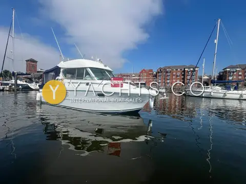 Jeanneau Merry Fisher 805: bow quarter view afloat in calm marina water with yachts and apartments behind