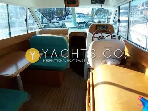 Jeanneau Merry Fisher 805: saloon with teal dinette seating, teak-effect sole and helm seat to starboard
