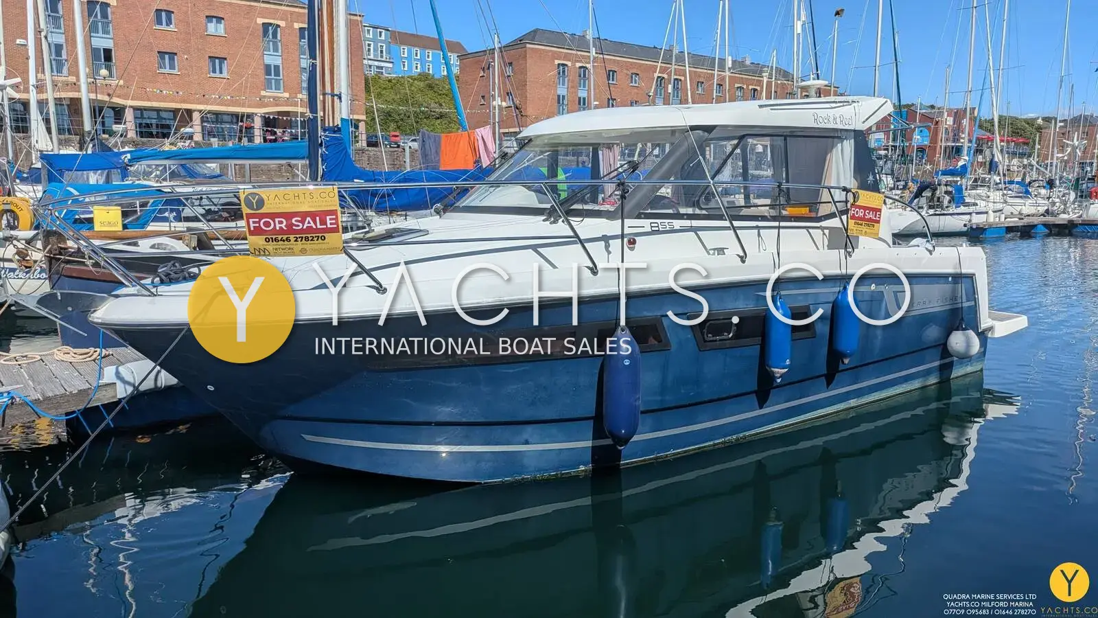Jeanneau Merry Fisher 855: blue-hulled sports boat with white superstructure moored in a marina beside brick buildings