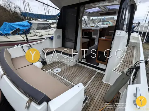 Jeanneau Merry Fisher 855: teak cockpit with beige seating leading through open sliding doors into the saloon