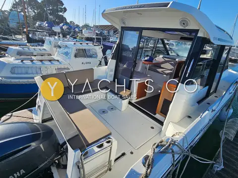 Jeanneau Merry Fisher 895: cockpit with grey U-shaped seating and open sliding door into the wheelhouse